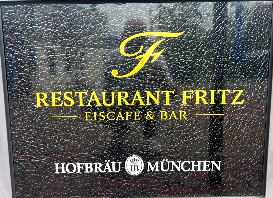 Das Schild vor der Tür: goldenes F, Restaurant Fritz, Eiscafé und Bar, darunter Hofbräu München.